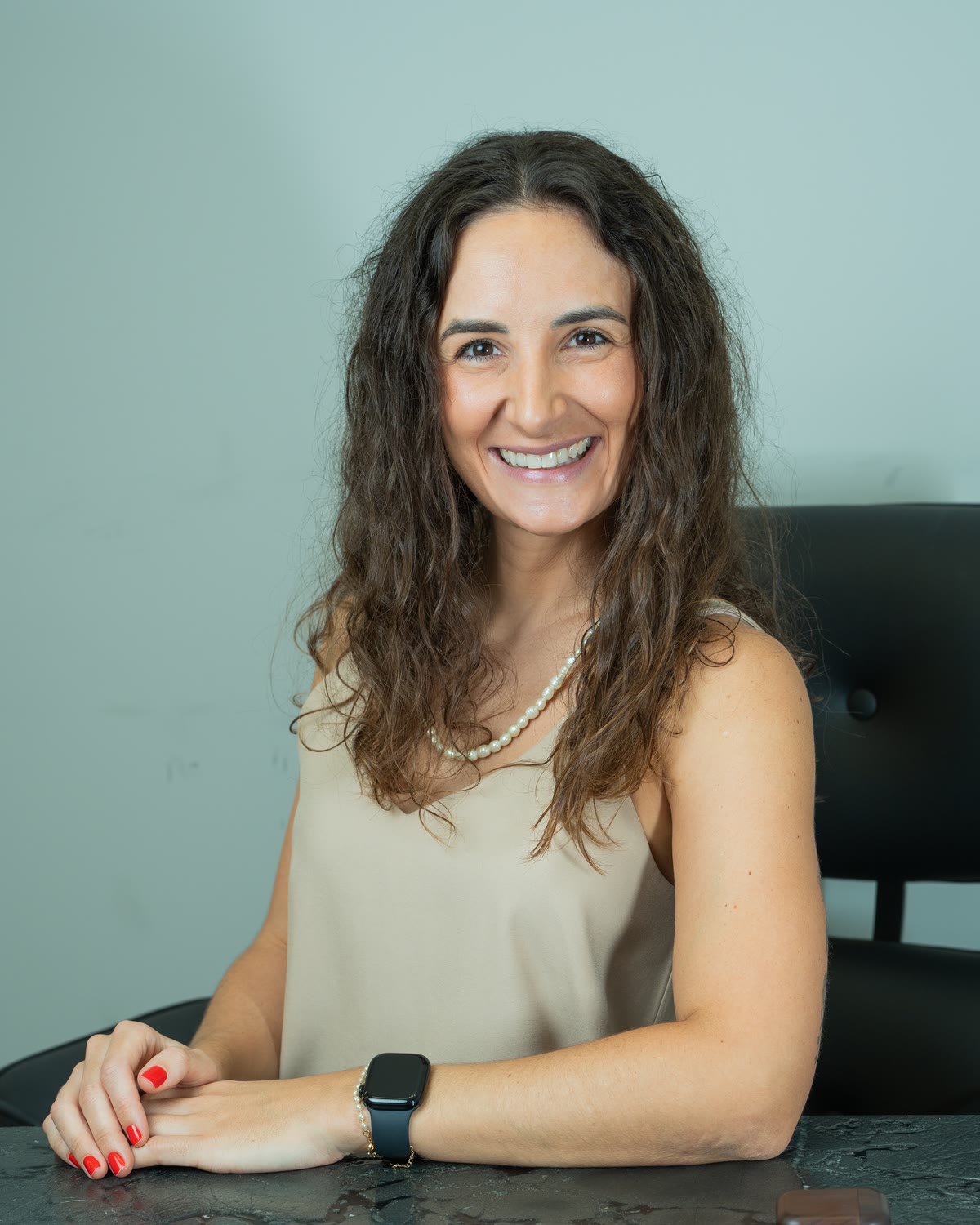 Dra. Ana Lucia Antonello sentada à mesa do consultório, sorrindo